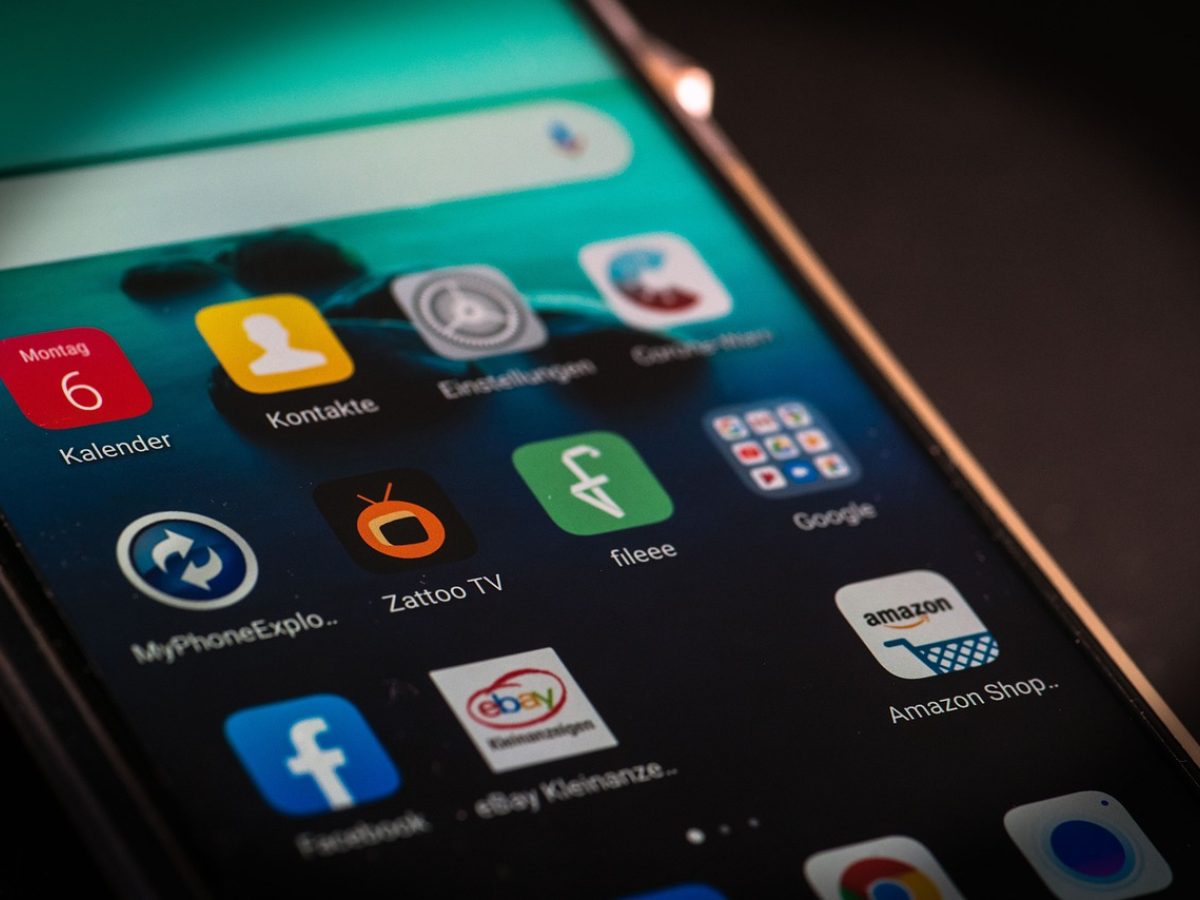 站长之家 App 主界面在一部竖屏手机上展开，首页排列着收录查询入口与权重趋势折线图，桌面木纹背景上有笔记本与咖啡杯，清晨侧光营造安静的办公氛围